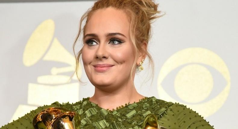 Adele poses in the press room with her five trophies, including the top two Grammys of Album and Record of the Year for her blockbuster hit Hello and the album 25