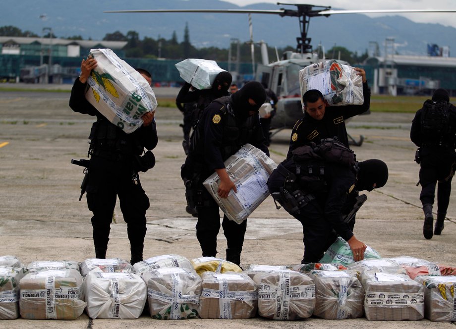 Police officers carry packages cocaine seized in Puerto Quetzal, at the air force base in Guatemala City, June 13, 2014.