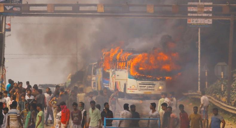 Protesters block a road after setting buses on fire during a demonstration against the Citizenship Amendment Bill in Howrah, on the outskirts of Kolkata