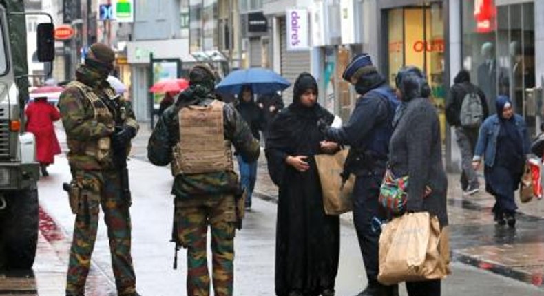 Belgian soldiers and a police officer control the documents of a woman in a shopping street in central Brussels, November 21, 2015, after security was tightened in Belgium following the fatal attacks in Paris.