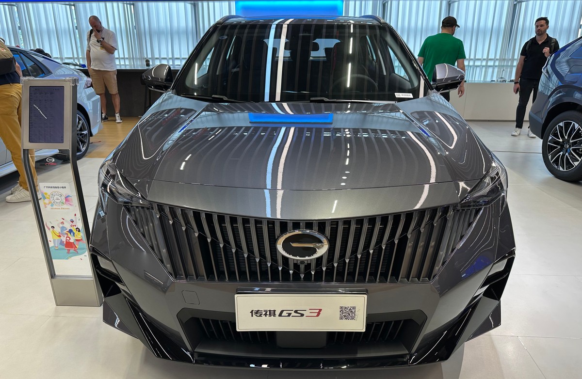 Szary SUV GAC Emzoom widok z przodu, agresywna stylistyka grilla, nowoczesne reflektory LED w salonie samochodowym