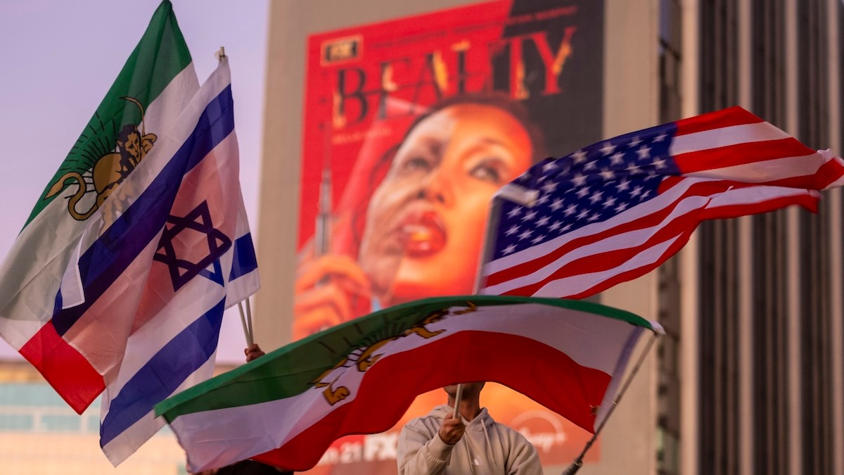 Protestujúci v LA stoja mávajú vlajkami USA, Izraela a Iránu počas zhromaždenia na podporu zmeny režimu v Iráne.