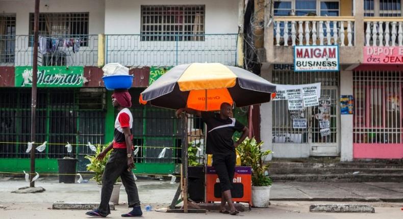 A man stands by a street stall in Kinshasa as another one walks past him on December 21, 2016