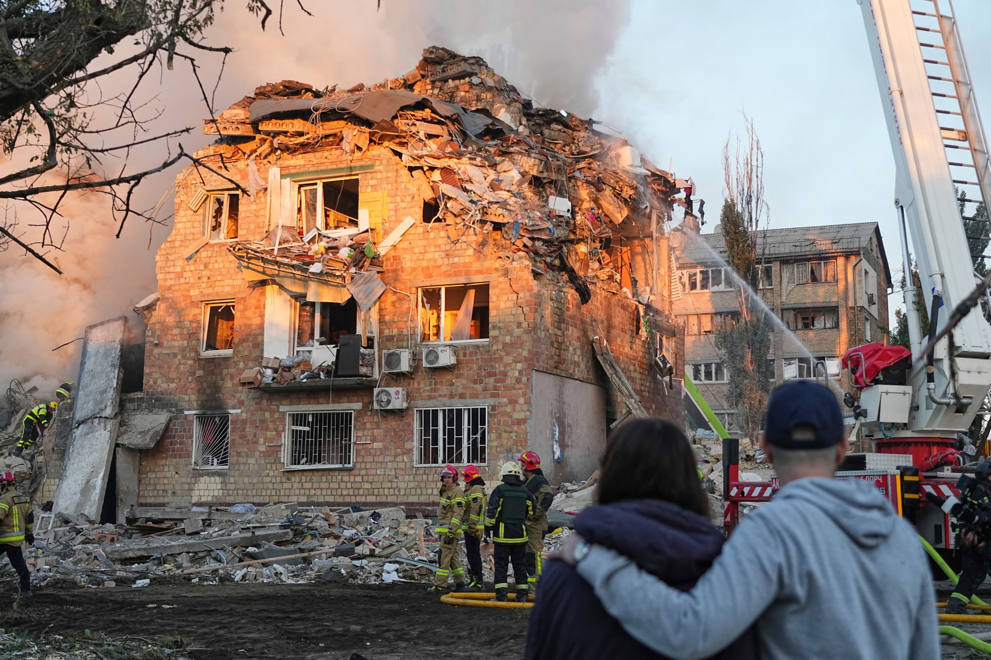 Hasiči pracujú na mieste horiacej budovy po ruskom útoku v Kyjeve.