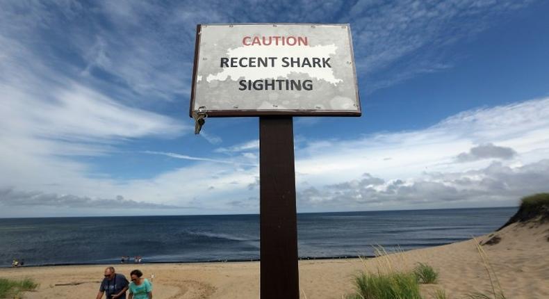 People exit the beach near a Recent Shark Sighting sign in 2012 at High Head Beach in Cape Cod, Massachusetts