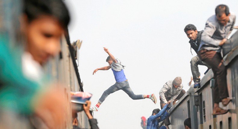 A man in Dhaka, Bangladesh leaps between the crowded train cars.