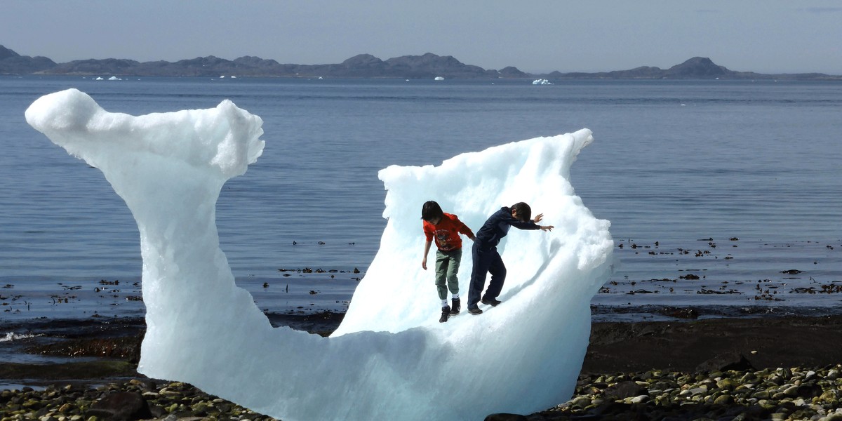 Children playing amid icebergs on the beach in Nuuk, Greenland.