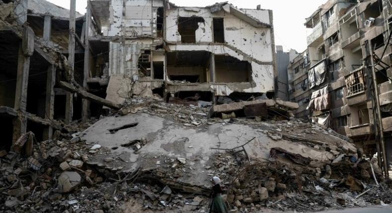 Syrian girls walk past destroyed buildings in the rebel-held town of Douma, on the eastern outskirts of Damascus, on May 6, 2017