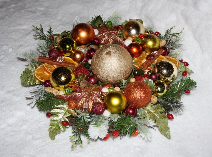 Okrągły stroik w odcieniach złota i miedzi, którego centralną ozdobą jest kulista świeca. Autorka: Marta Jarosińska-Mańka