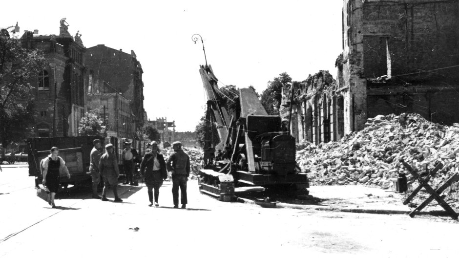 Warszawa, 1946 r. Usuwanie gruzu z ul. Królewskiej. Z lewej strony widoczny fragment budynku Zachęty, z prawej - widoczne kamienice zajmujące narożnik pl. Piłsudskiego