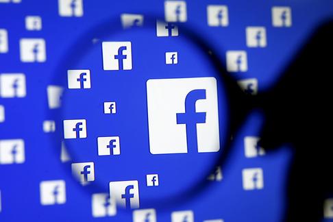 A man poses with a magnifier in front of a Facebook logo on display in this illustration taken in Sa
