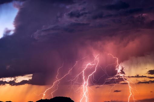 Lightning bolts strike from a sunset storm