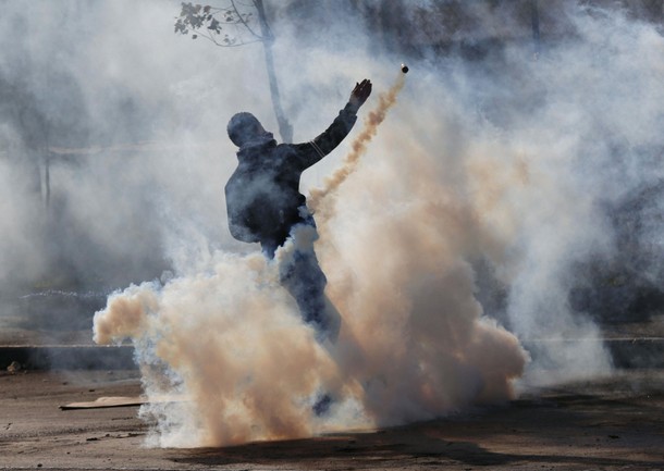 Palestinian protester hurls back a tear gas canister fired by Israeli troops during clashes in the W