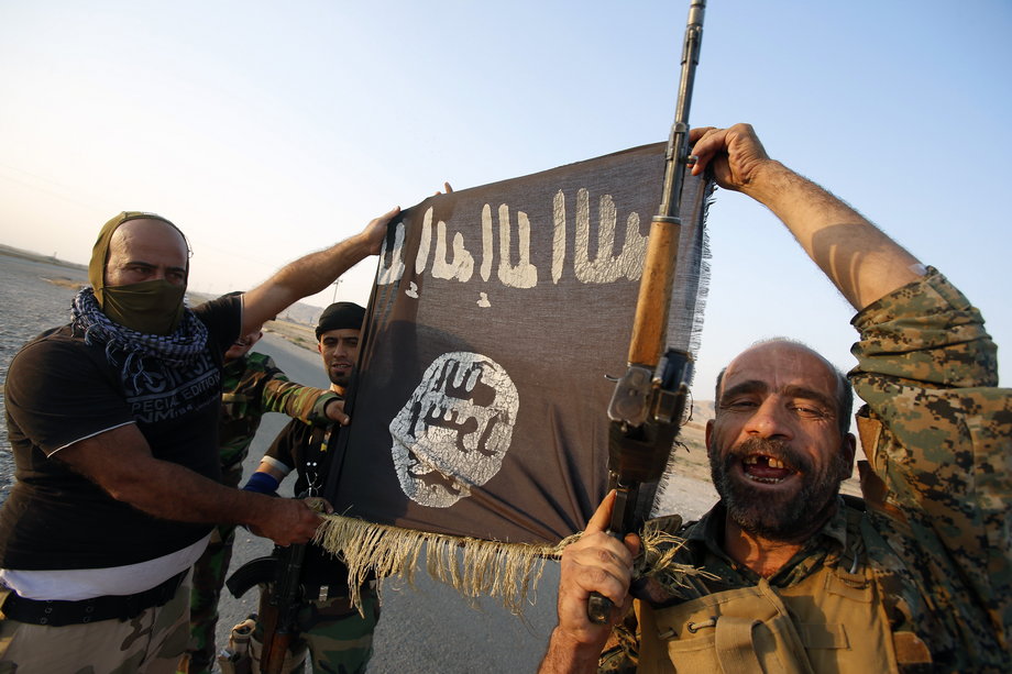 Iraqi Shiite militia fighters hold the Islamic State flag as they celebrate after breaking the siege of Amerli by ISIS militants, September 1, 2014.