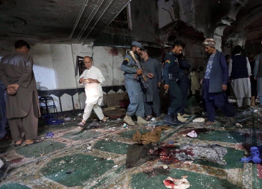 Afghan policemen and relatives inspect at the site of a suicide attack in Herat, Afghanistan