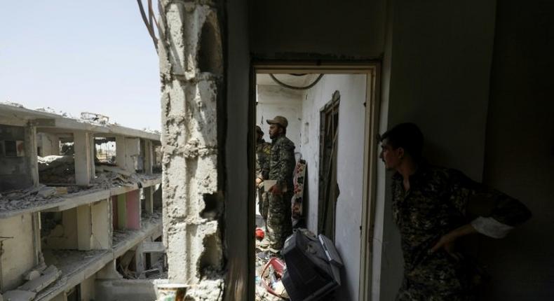 Members of the US-backed Syrian Democratic Forces move through destroyed buildings in Raqa on July 28, 2017