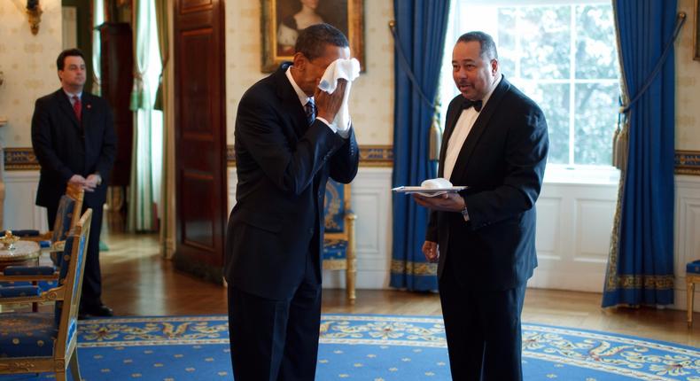 President Barack Obama wipes his face with a cloth handed to him by Von Everett, the White House butler.