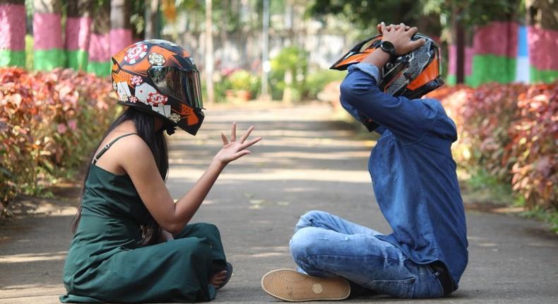 Photo of a couple wearing helmets, sitting on a pavement in a park [Image Credit: Professional QP]