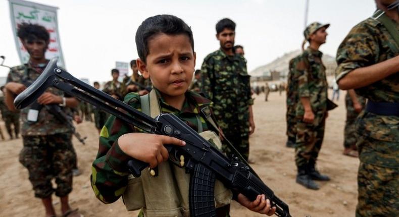 A Yemeni boy poses with a Kalashnikov assault rifle during a gathering of newly-recruited Huthi fighters in the capital Sanaa. A new UN report has flagged the vulnerability of children living in war zones mobilize more fighters to battlefronts in the war against pro-government forces in several Yemeni cities, on July 16, 2017.