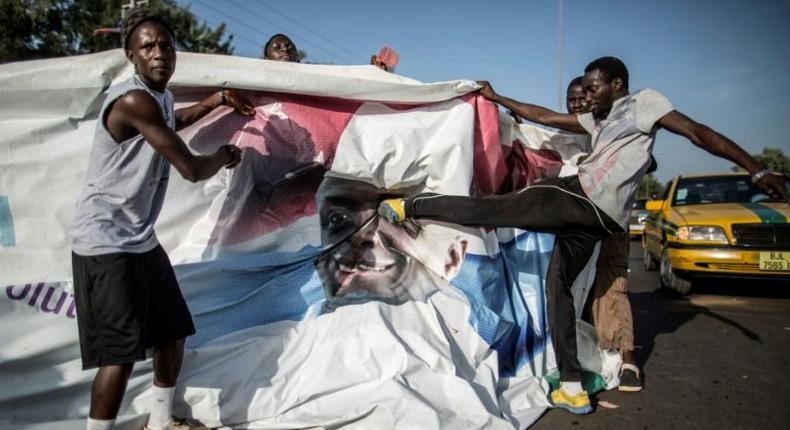 A supporter of the newly elected Gambia President Adama Barrow kicks a poster of the exiting leader Yahya Jammeh in Serekunda