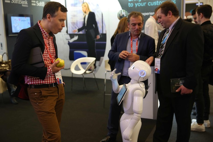 Przy stoisku japońskiej firmy SoftBank Robotics goście rozmawiają z robotem 'Pepper', zaprojektowanym w celu powitania klientów w przestrzeniach komercyjnych.
