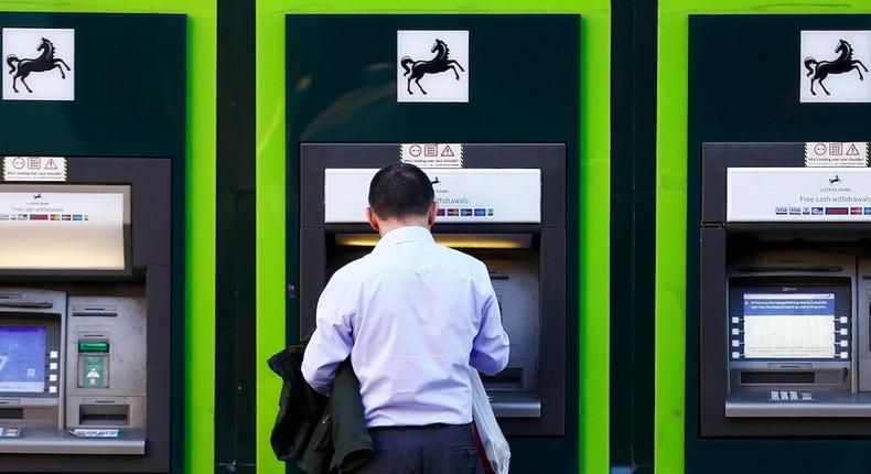 A man uses an ATM outside a branch of Lloyds Bank in London.