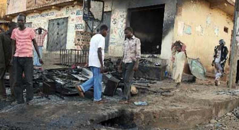 People walk past a burnt house in Nigeria's central Plateau State's capital Jos, November 30, 2008