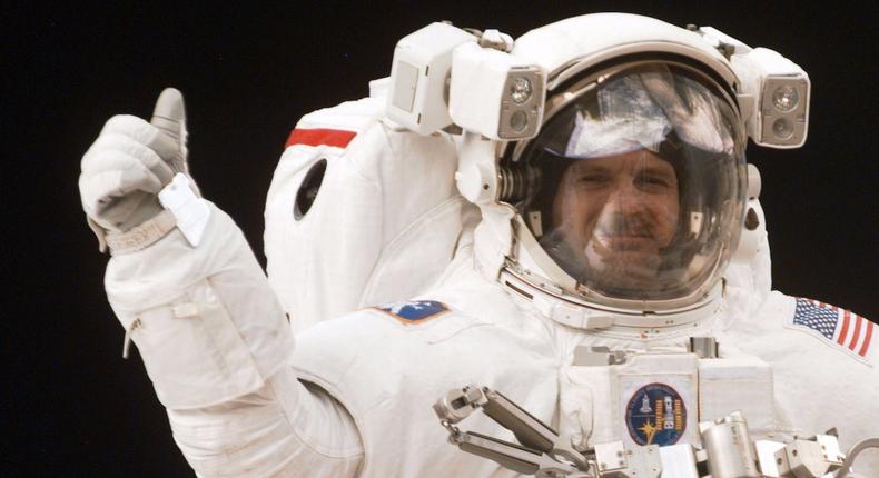 An astronaut in space flashes a thumbs-up sign.