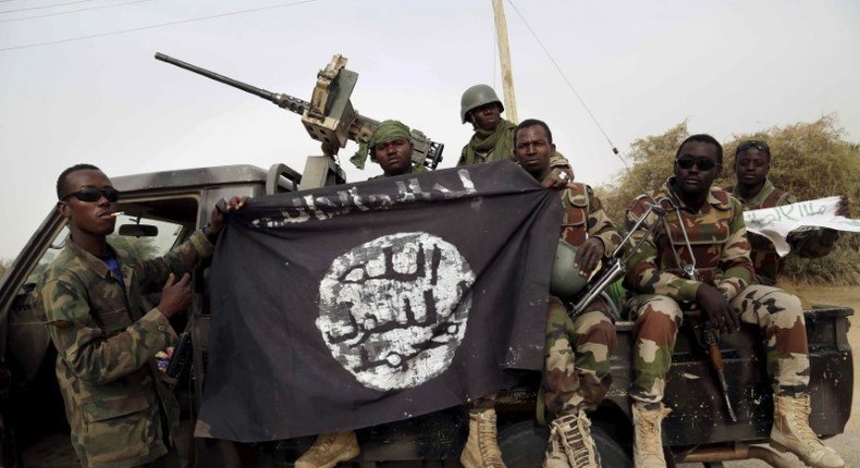 Nigerian soldiers hold up a Boko Haram flag that they had seized in the recently retaken town of Damasak, Nigeria, March 18, 2015. REUTERS/Emmanuel Braun