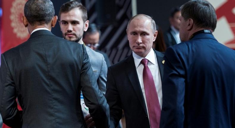 US President Barack Obama (L) and Russia's President Vladimir Putin (2ndR) shake hands before an economic leaders meeting on November 20, 2016 in Lima