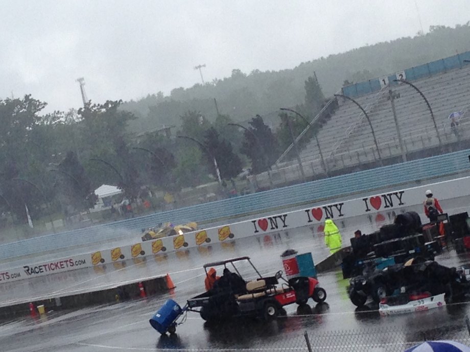 At high speeds, the race cars kick up rooster tails of spray from the wet track.