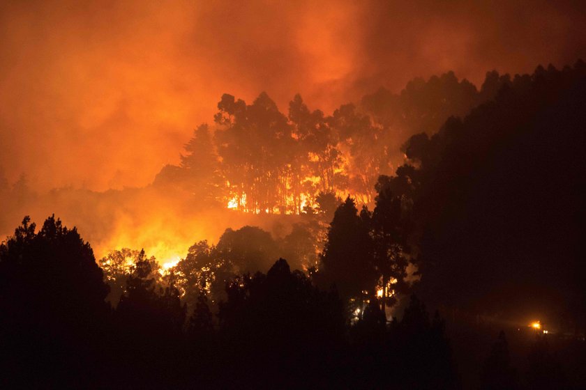 Flames and smoke from a forest fire are seen in the village of Valleseco