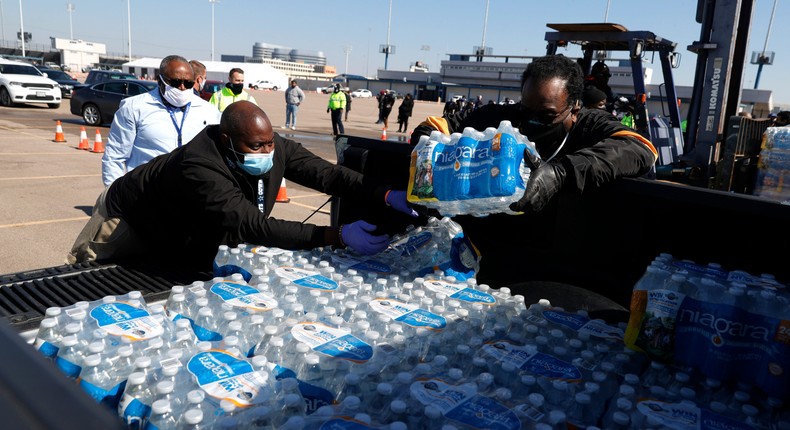 Volunteers load cases of water into the bed of a truck during a mass water distribution at Delmar Stadium on February 19, 2021.
