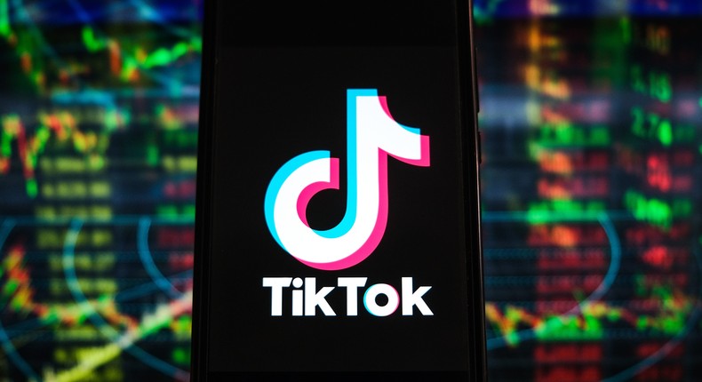 In this photo illustration, a TikTok logo is displayed on a smartphone with stock market percentages in the background.
