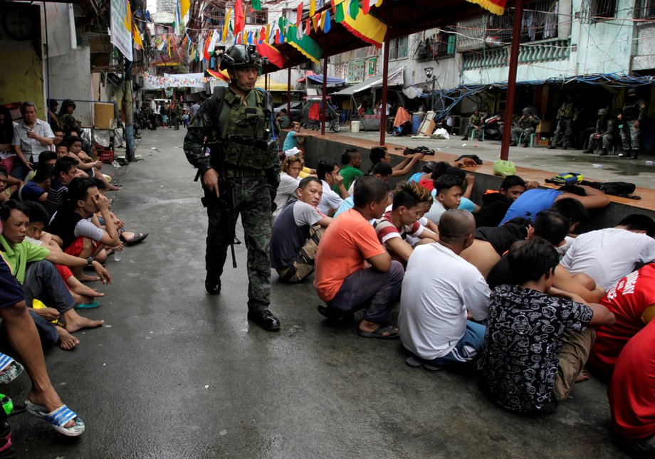 People sit on a street after they were rounded up as they wait to be brought to a police station for verification if they are involved with drugs, after police sources and local media reported that people were killed during a raid, in Manila, Philippines, October 7, 2016.