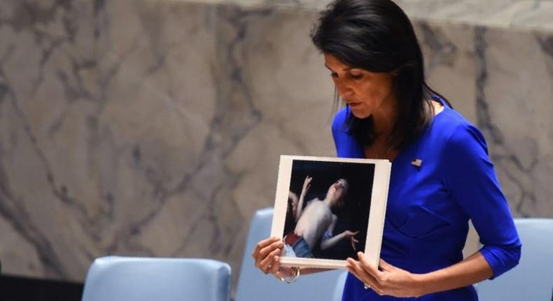 US Ambassador to the UN Nikki Haley holds photos of victims as she speaks at the UN Security Council on April 5, 2017, about the suspected deadly chemical attack that killed civilians, including children, in Syria