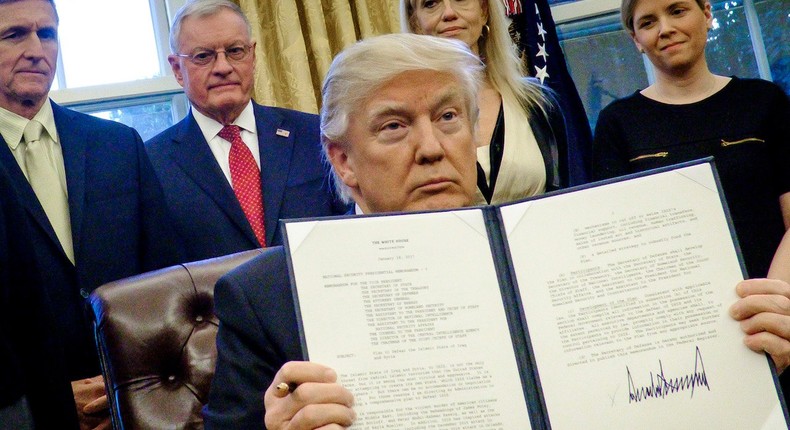 Donald Trump signs an executive order in the Oval Office.