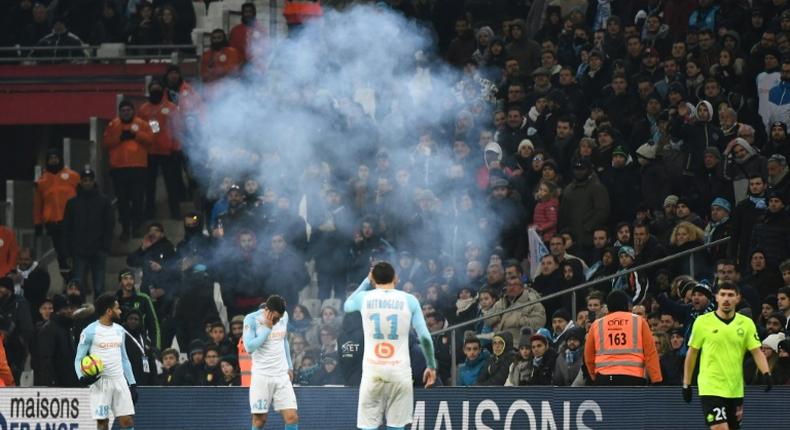 Marseille players Jordan Amavi, Kevin Strootman and Kostas Mitroglou react after a firecracker explodes beside the pitch during their team's defeat against Lille on Friday