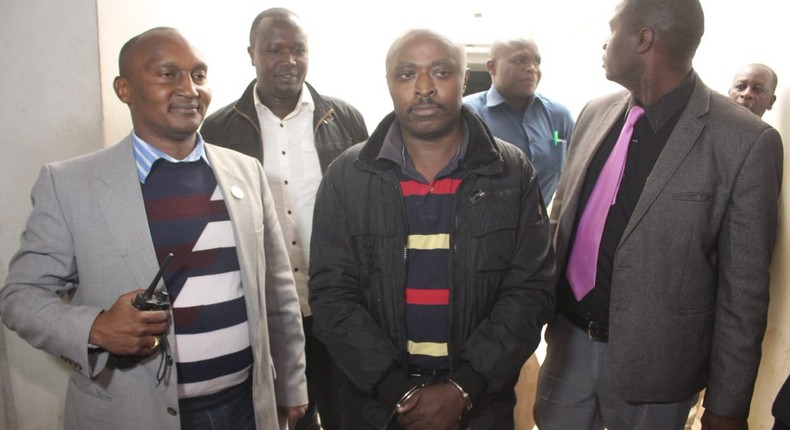 Mugo wa Wairimu escorted by police officers during his court appearance