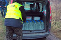 Funkcjonariusz KAS ładuje zarekwirowane butelki do bagażnika