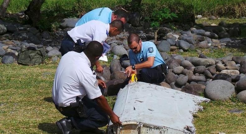 File picture shows French gendarmes and police inspecting a large piece of plane debris which was found on the beach in Saint-Andre, on the French Indian Ocean island of La Reunion, July 29, 2015. 