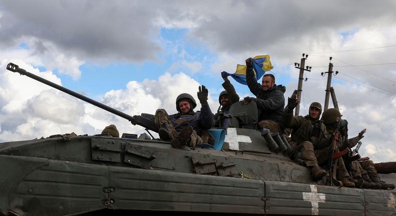Ukrainian soldiers wave a national flag as they ride on a personnel armoured carrier on a road near Lyman, Donetsk region on October 4, 2022, amid the Russian invasion of Ukraine.ANATOLII STEPANOV/AFP via Getty Images