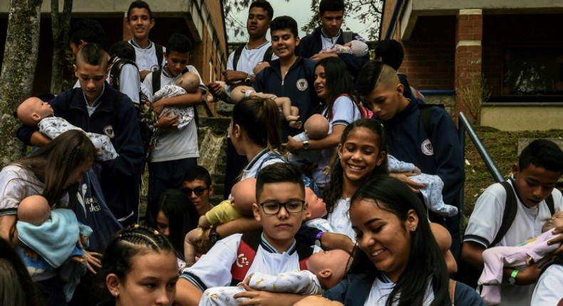 Students carry their babies during a break at a school in Caldas municipality, Colombia on May 17, 2019