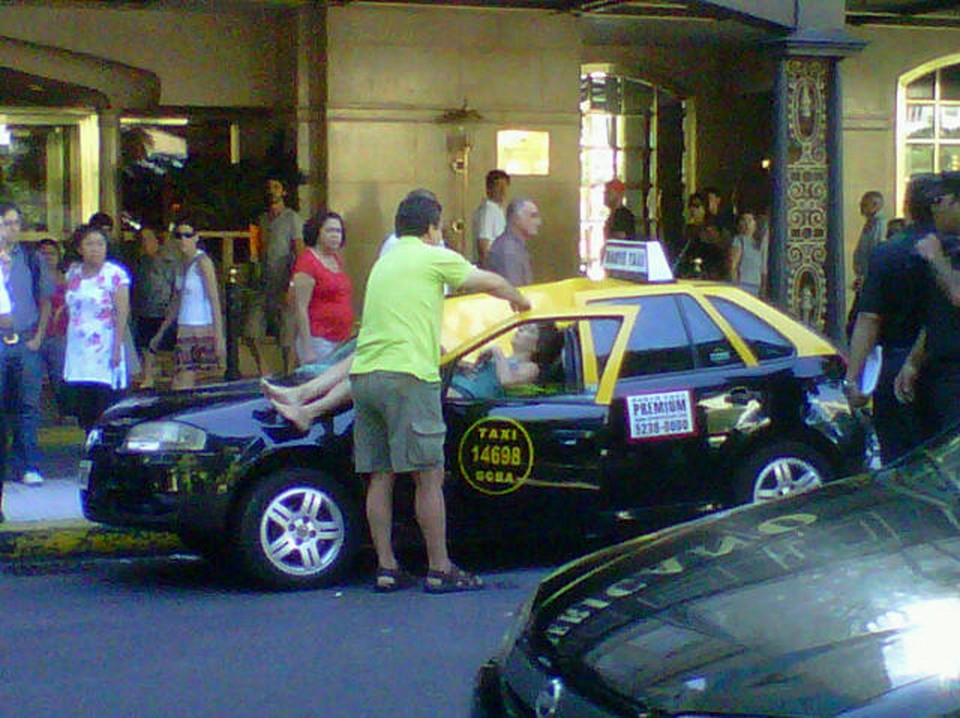 A woman lies injured atop a taxi where she fell from the 23rd floor of the Hotel Panamericano in Buenos Aires