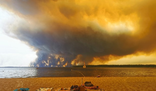 Posetioci plaže odmaraju se na plaži Mučik na obali jezera Lakano u Lakanou, na jugozapadu Francuske, dok požar besni u Žirondi, 24. jul 2026.