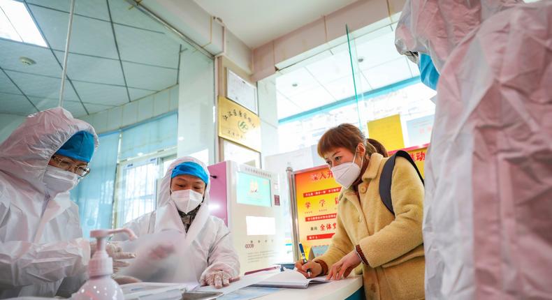 Medical workers in protective gear talk with a woman suspected of being ill with a coronavirus at a community health station in Wuhan in central China's Hubei Province, Monday, Jan. 27, 2020. China on Monday expanded sweeping efforts to contain a viral disease by extending the Lunar New Year holiday to keep the public at home and avoid spreading infection. (Chinatopix via AP)