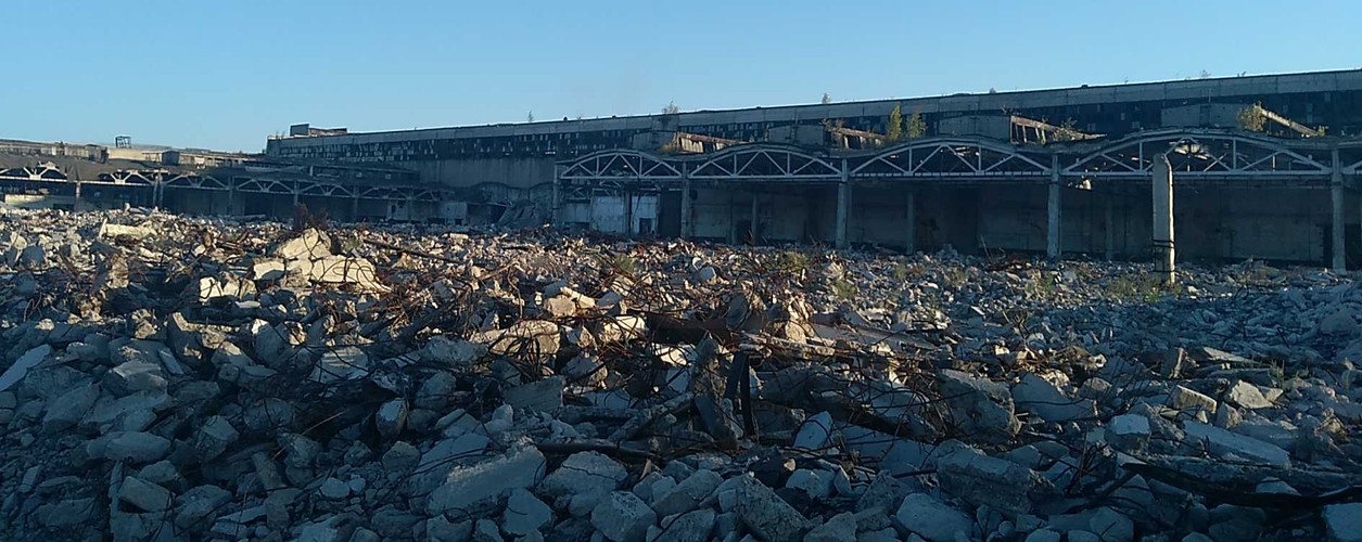 <br></br>
Zakład doprowadził do bankructwa na długo przed wojną ówczesny gubernator obwodu ługańskiego Ołeksandr Jefremow, wpędzając go w sztucznie wytworzone długi. Polityk Partii Regionów kazał kierownictwu zakładu kupować gaz po zawyżonych cenach od kontrolowanej przez siebie spółki. Po upadku fabryka została rozkradziona. Lokalni aktywiści uważają, że taki był cel doprowadzenia go do bankructwa. Ktoś wykopał metalowe rury, wywiózł cegły, materiały budowlane, a nawet piasek.
<br></br>
Na teren fabryki przez otwartą bramę może wejść każdy. Dym unoszący się nad ruinami na środku zdjęcia świadczy o obecności szabrowników wypalających miedź z kabli. Nasz przewodnik, lokalny aktywista Wołodymyr Syrotin, podczas naszej wizyty na pofabrycznym terenie wezwał do nich policję i dziennikarzy z lokalnej telewizji. Przed szabrem nie uchronił nawet ochroniarz, patrolujący teren fabryki starym, zielonym żyguli.
<br></br>