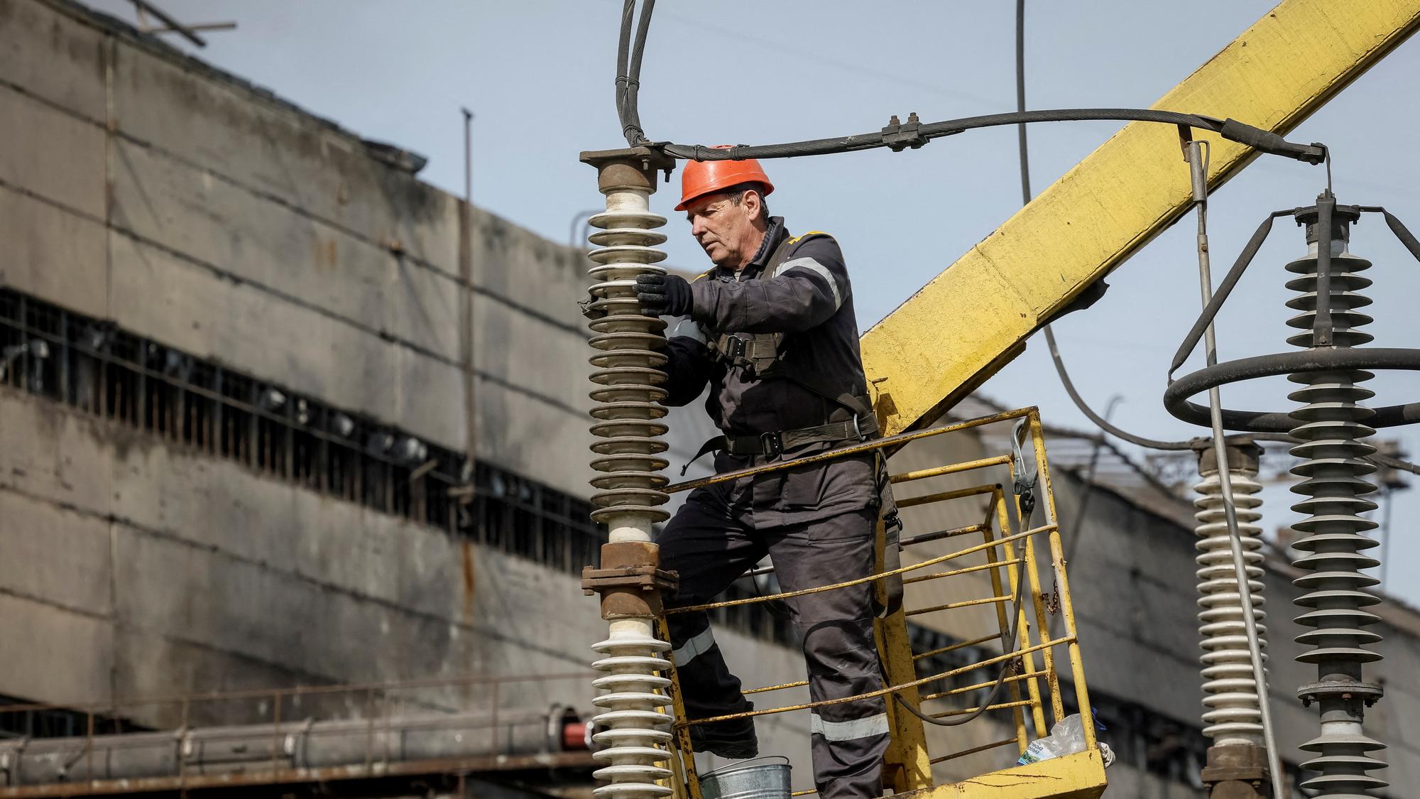 Muž opravuje poškodenú energetickú infraštruktúru po ruskom útoku na Ukrajine