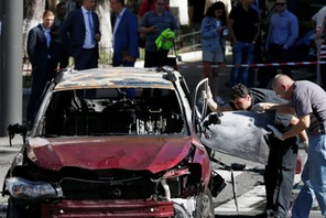 Investigators inspect a damaged car at site where journalist Pavel Sheremet was killed by a car bomb