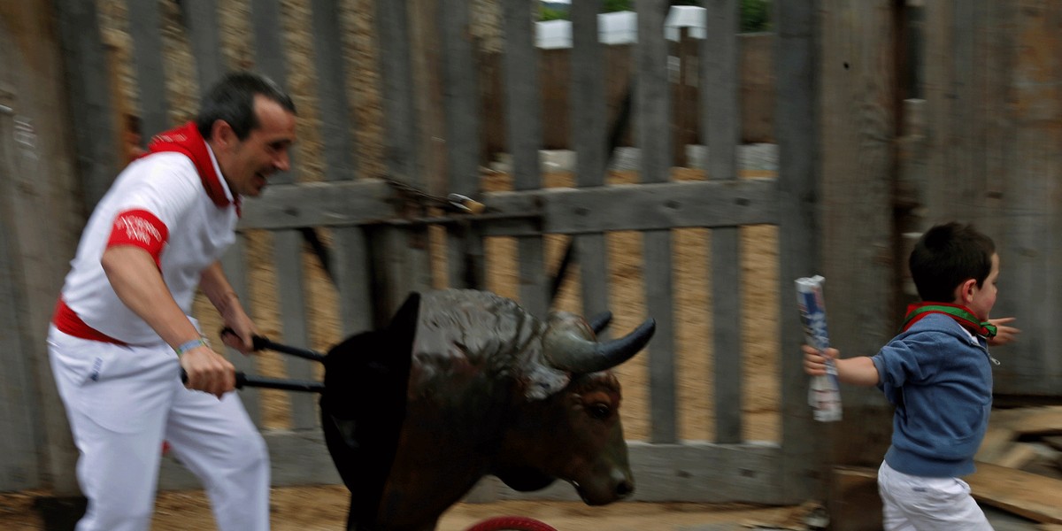 A boy running from a toy bull while taking part in the Encierro Txiki (Little Bull Run) during the San Fermin festival in Pamplona, Spain.